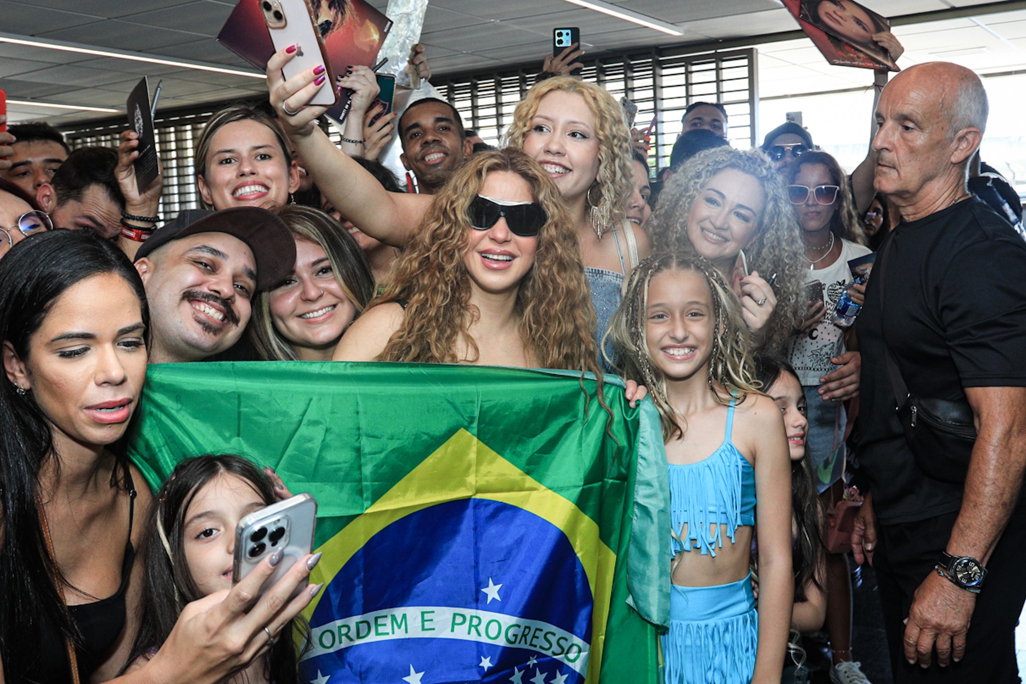 Shakira desembarca no Galeão para show no Rio e posa com fãs e a bandeira do Brasil